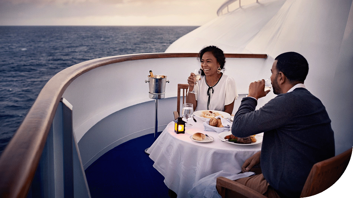 A couple enjoys and sunlit dining experience on a Princess ship balcony.