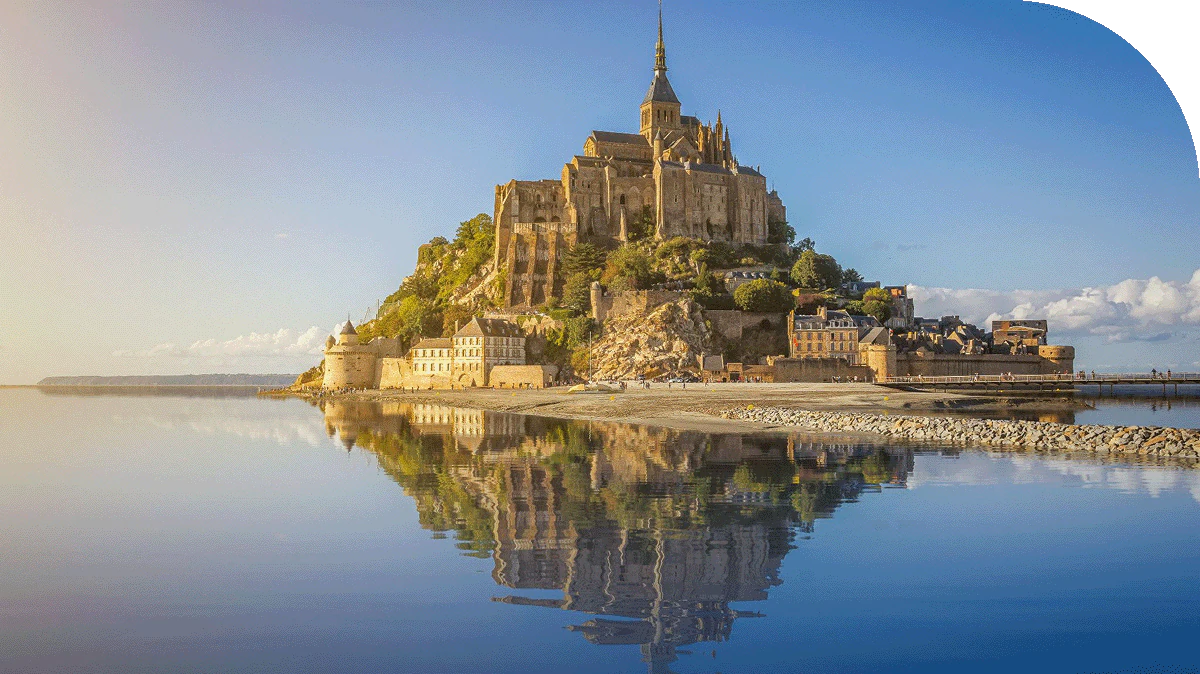 A distant view of Le Mont Saint Michel, France reflected in the water.
