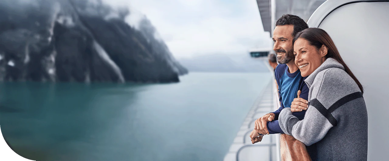 A couple on a balcony of a Princess ship, cruising through Alaska.