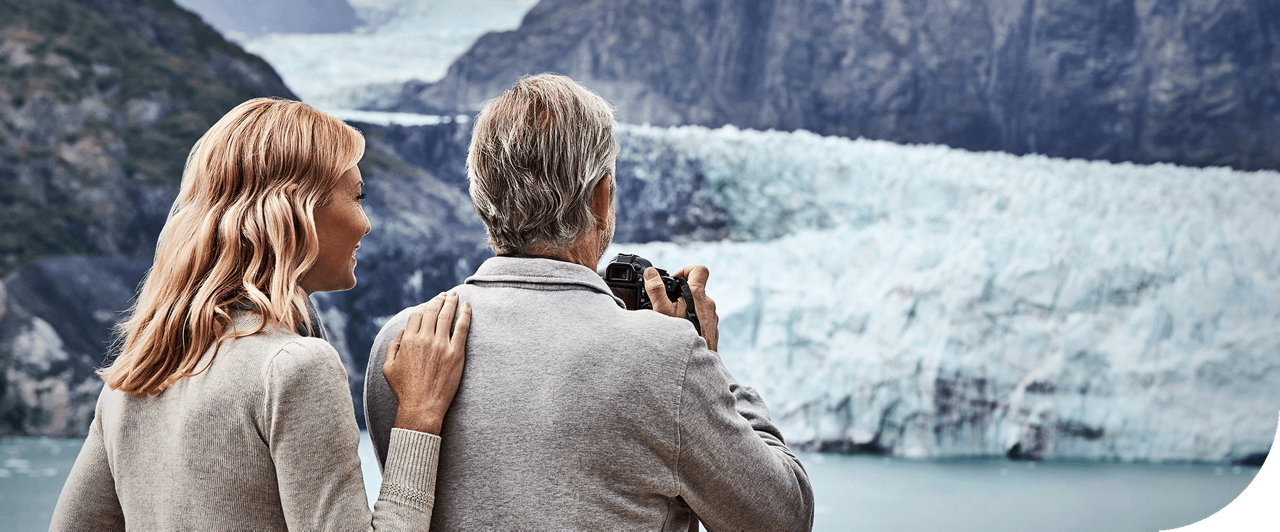 Couple on deck taking photos of glaciers in Alaska Bay.