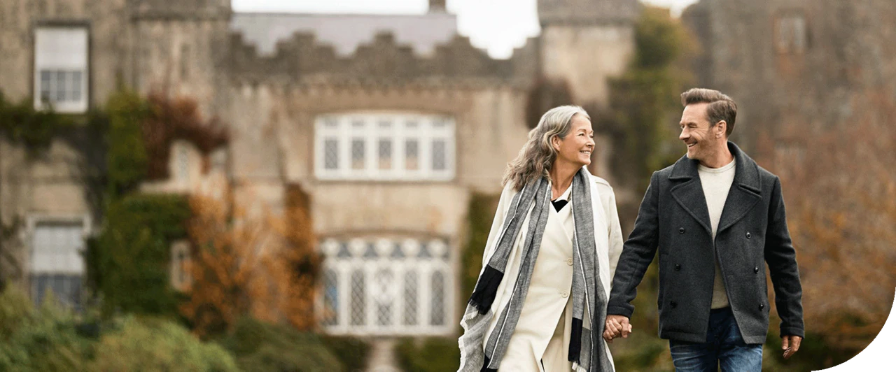 A happy couple strolls alongside Malahide Castle, Ireland.