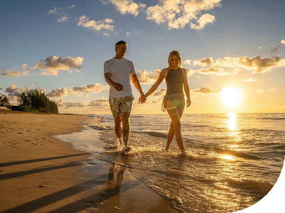 A couple strolls along a Caribbean beach at sunset.