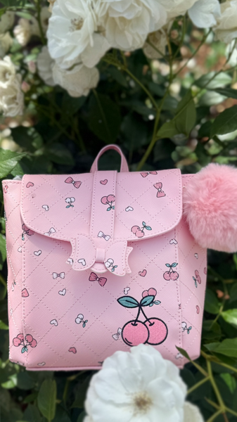 Pink cherry print mini backpack with pink charm in garden. 
