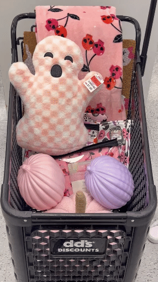 Black shopping cart filled with halloween ghost and pumpkin throw pillows. 