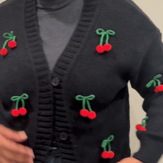 Person wearing a black sweater with red cherries