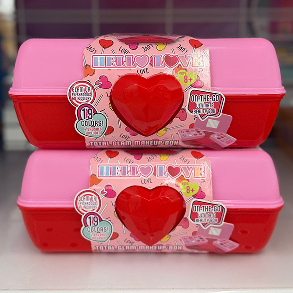 Two identical pink and red makeup kits for kids, each with a red heart-shaped center and colorful Valentine-themed packaging advertising “19 colors” and “on-the-go beauty.”