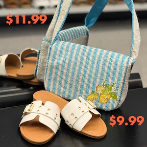 A blue‑and‑white striped crossbody bag with an embroidered lemons for $11.99 sits beside white slide sandals for $9.99 on a retail display.