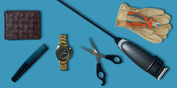 A flat lay of assorted accessories featuring a brown wallet, gold-tone wristwatch, comb, scissors, gloves, pliers, and an electric grooming trimmer displayed on a blue surface.
