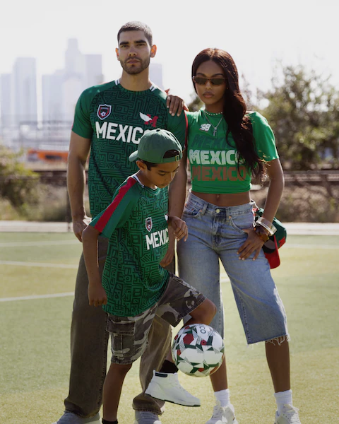 A group of three individuals wear green Mexico-themed soccer jerseys on a field, with one holding a soccer ball in front.