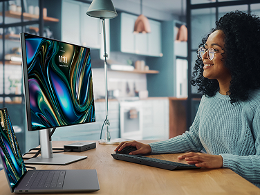 A Graphic Designer working on a Dell 16 Premium Laptop with a WD22TB4 docking station, 24 Ultrasharp Monitor, Pro Premium Collaboration Keyboard and Mouse.