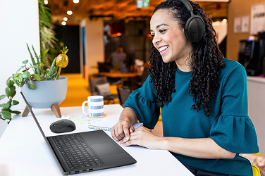 A happy office worker engaged in a video call on a Dell laptop.