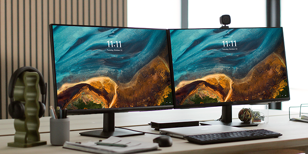 A Dell laptop computer, with two monitors, a dock, webcam, wireless keyboard and mouse on an office desk.