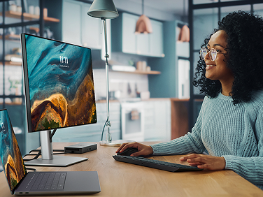 A Graphic Designer working on a Dell 16 Premium Laptop with a WD22TB4 docking station, 24 Ultrasharp Monitor, Pro Premium Collaboration Keyboard and Mouse.