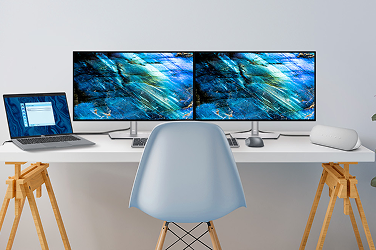 A desk with two Dell monitors, a laptop, wired speaker, wireless keyboard and mouse.