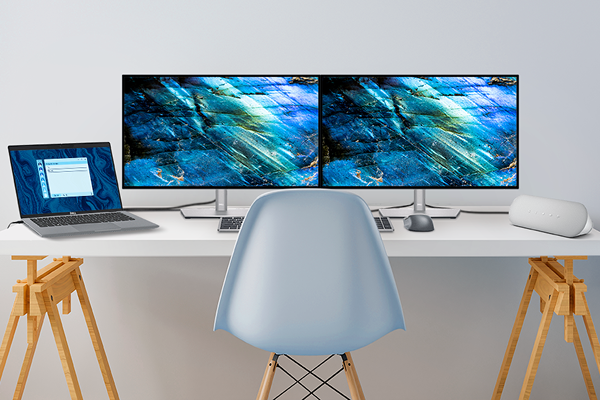 A desk with two Dell monitors, a laptop, wired speaker, wireless keyboard and mouse.