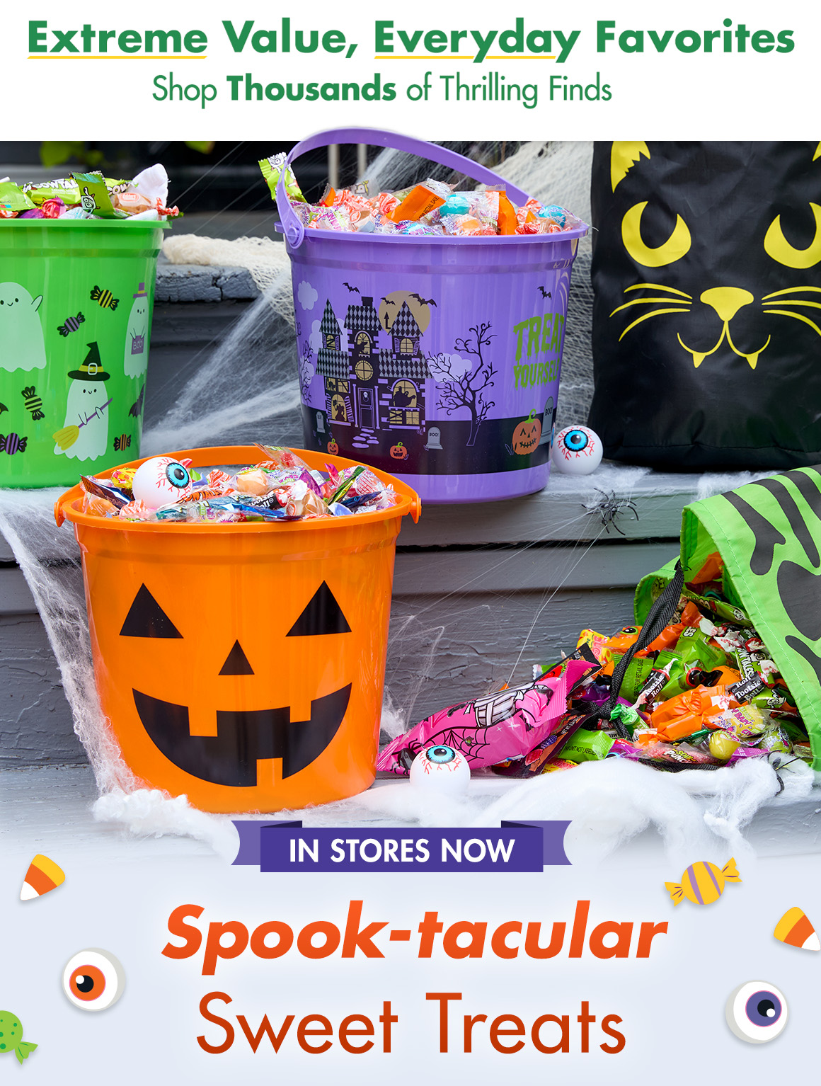 Halloween buckets and bags filled with candy surrounded by faux spider webs, plastic spiders and plastic eyeballs.