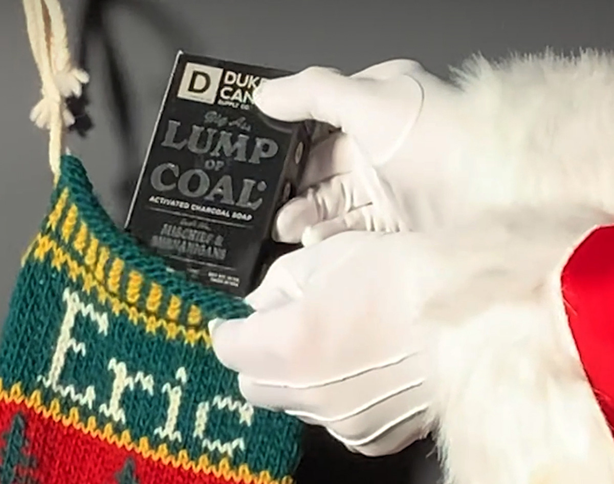 Santa putting a Big Ass Lump of Coal Brick in a stocking.