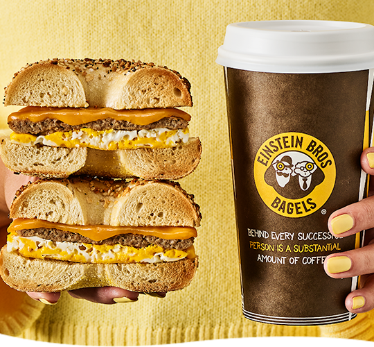 Person holding classic egg sandwich and branded beverage cup