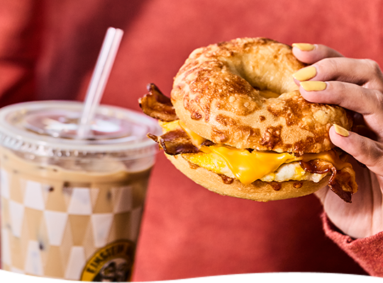Hand holding a sandwich and iced beverage