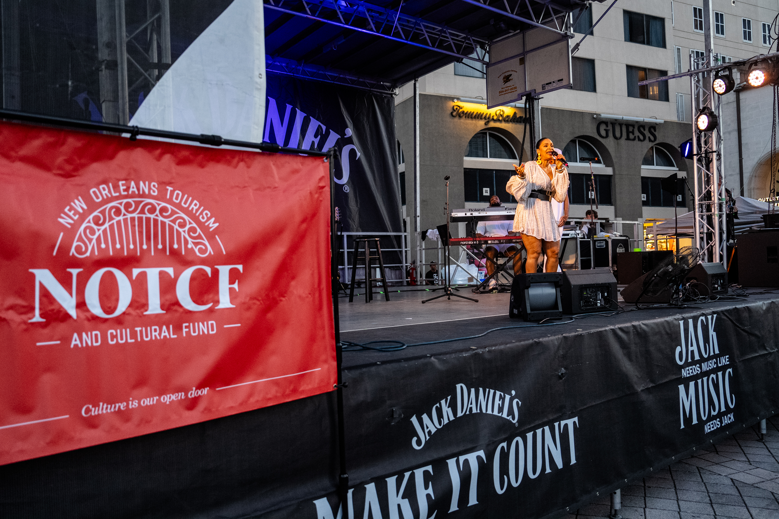 A banner for New Orleans Tourism and Cultural Fund is displayed during the performance of Teedra Moses at French Quarter Festival 2024