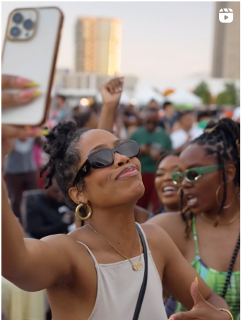 a woman holding up a cell phone in a crowd of people