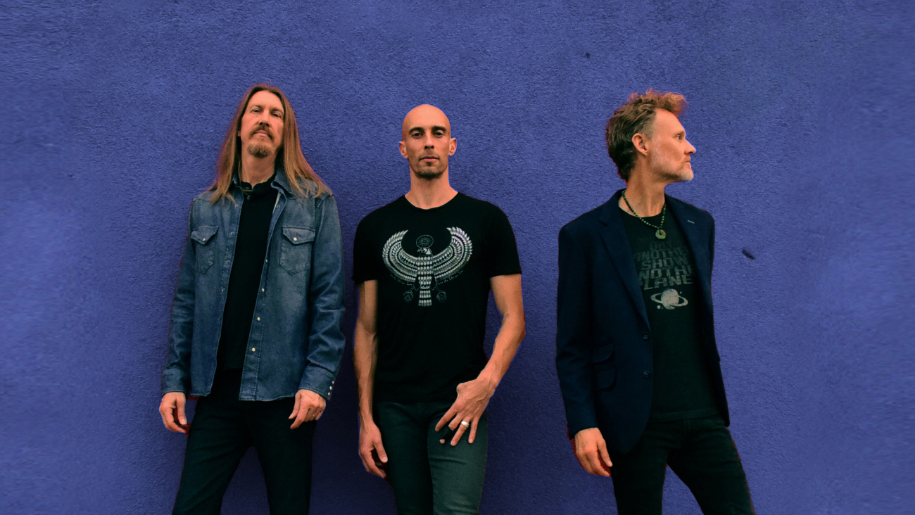 the wood brothers standing in front of a blue wall