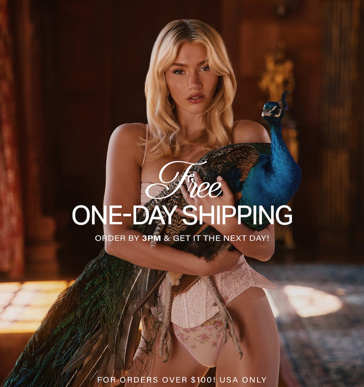 Blonde woman in pink lace lingerie embracing a vibrant blue-green peacock. Shop sexy lingerie with free one-day shipping over $100.