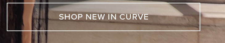 Muted brown and dark blurred background detail with white text 'SHOP NEW IN CURVE' prominently displayed. Shop new plus size clothing arrivals now.
