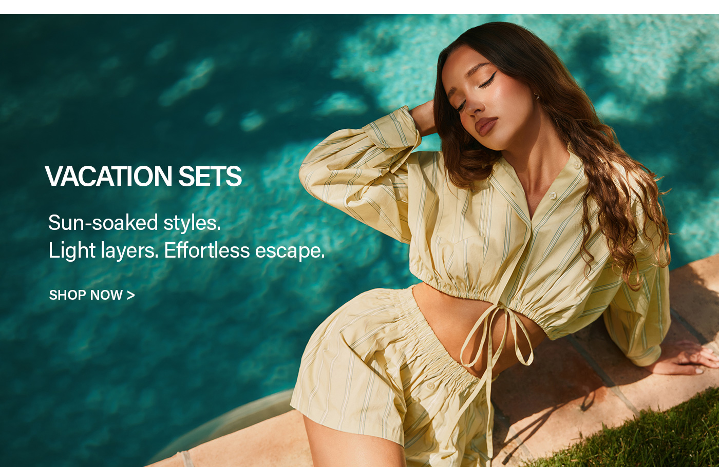 Relaxed woman in a pale yellow striped crop top and shorts vacation set, basking by a teal pool. Discover sun-soaked summer styles.