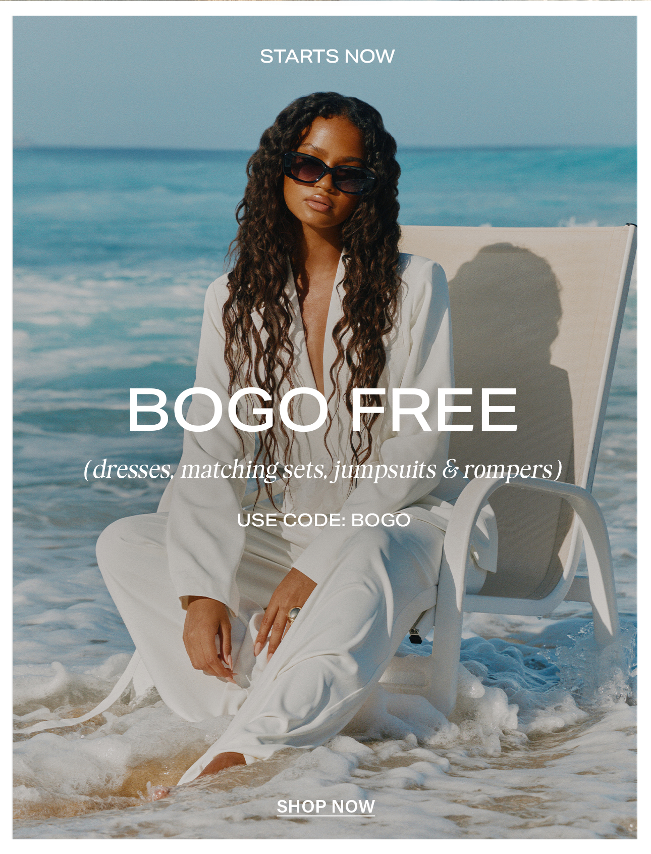 Woman in white pantsuit and sunglasses sitting in ocean waves, promoting BOGO FREE sale on dresses, matching sets, jumpsuits, rompers.