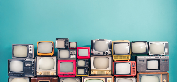 Retro TVs from various time periods-from the 1950s-1990s- stacked in front of a light teal background