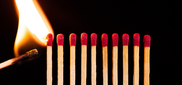 A burning matchstick in the process of lighting 10 additional matchsticks all in a row