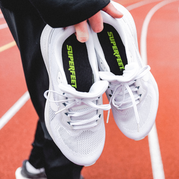 Man putting Superfeet insoles in shoes on a track