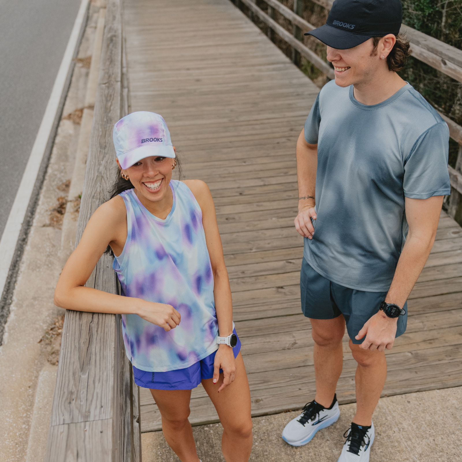 Two runners wearing hats on a bridge