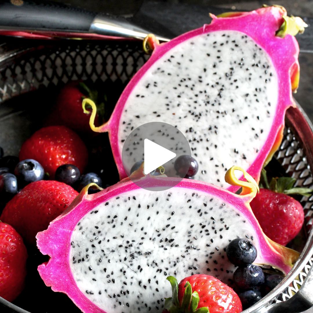 Sliced dragon fruit halves in bowl with strawberries and blueberries