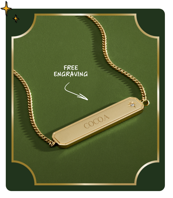Closeup of gold necklace with nameplate pendant against dark green seasonal background, arrow pointing to pendant with “free engraving”