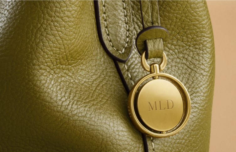 Close-up of green pebbled leather with gold charm engraved with initials MLD