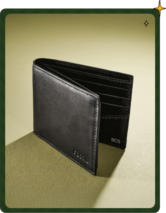 Black leather wallet standing open showing credit card slots, Fossil logo embossed, and personalized initials inside