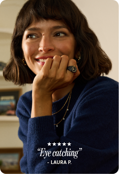 Close-up of a smiling woman with chin-length hair, hand on chin, wearing a black and gold watch ring on her left hand, with five stars and the review “eye catching”.