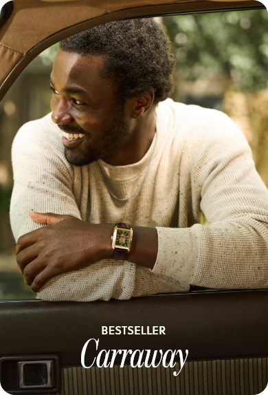 Close-up portrait of a man smiling looking off to the side with arms folded a leather and gold case Fossil watch on wrist with text Bestseller Carraway