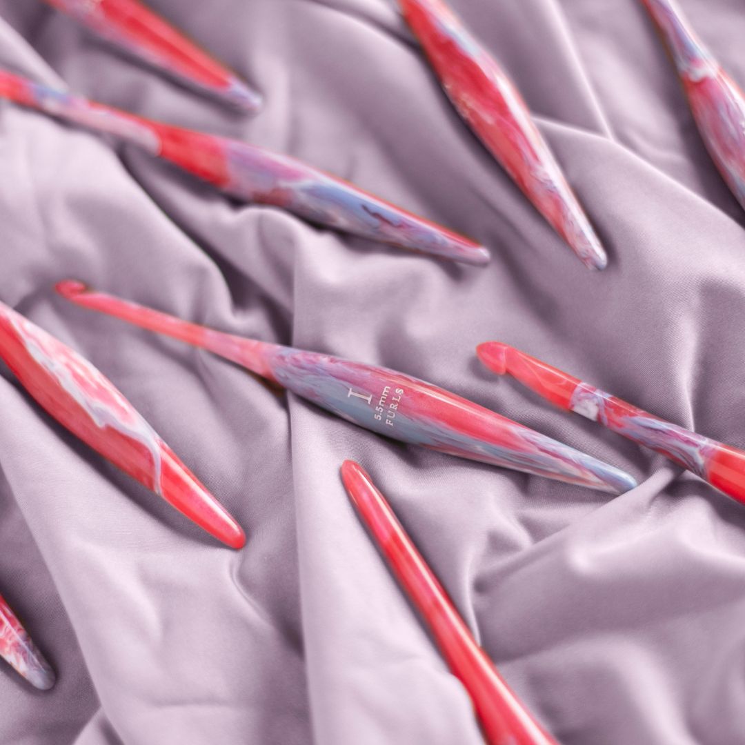 Pink/purple crochet hooks on a purple fabric background