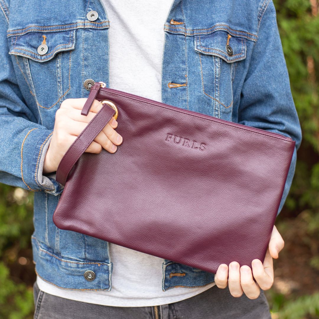 hands holding a purple leather clutch