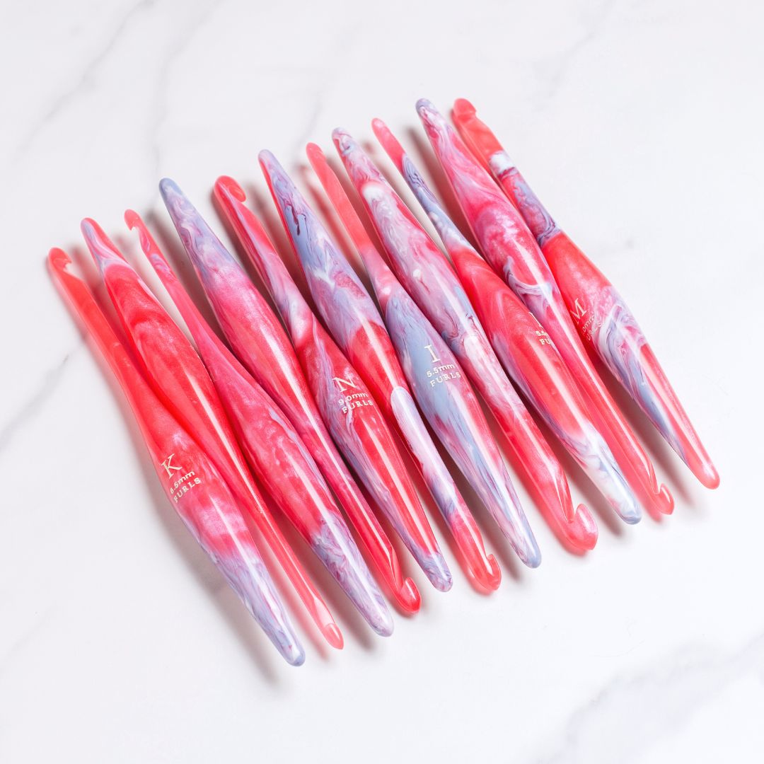 Pink/purple crochet hooks on a purple fabric background