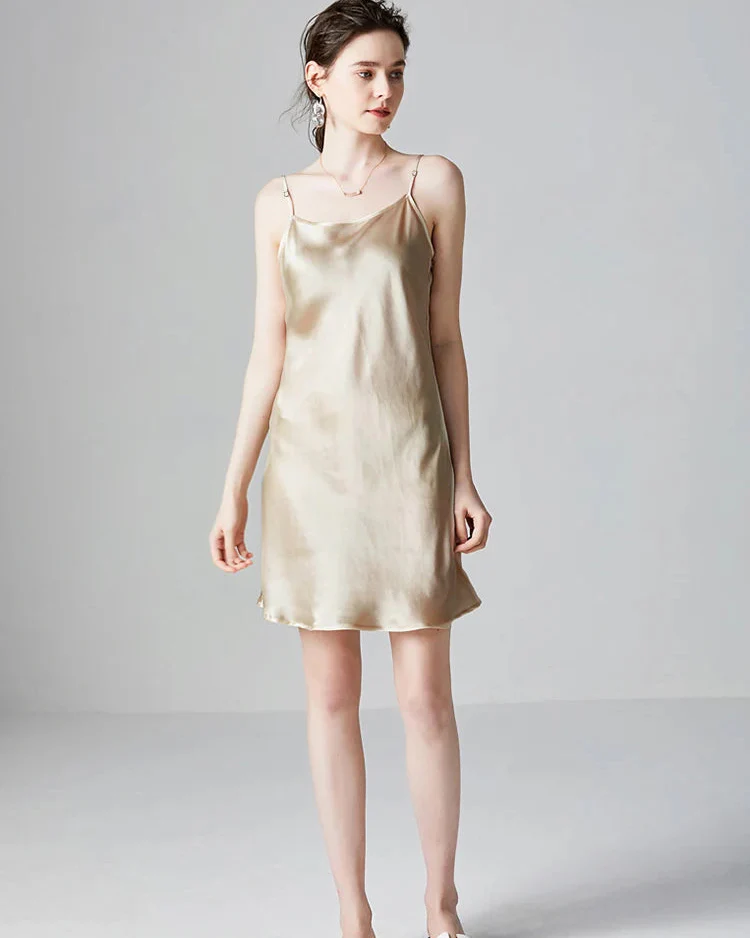 A woman models a short, champagne-colored silk slip dress.