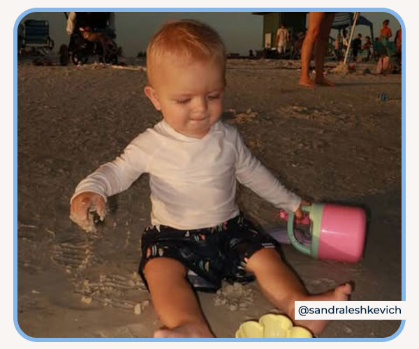 Baby playing in the sand wearing Gerber Rashguard