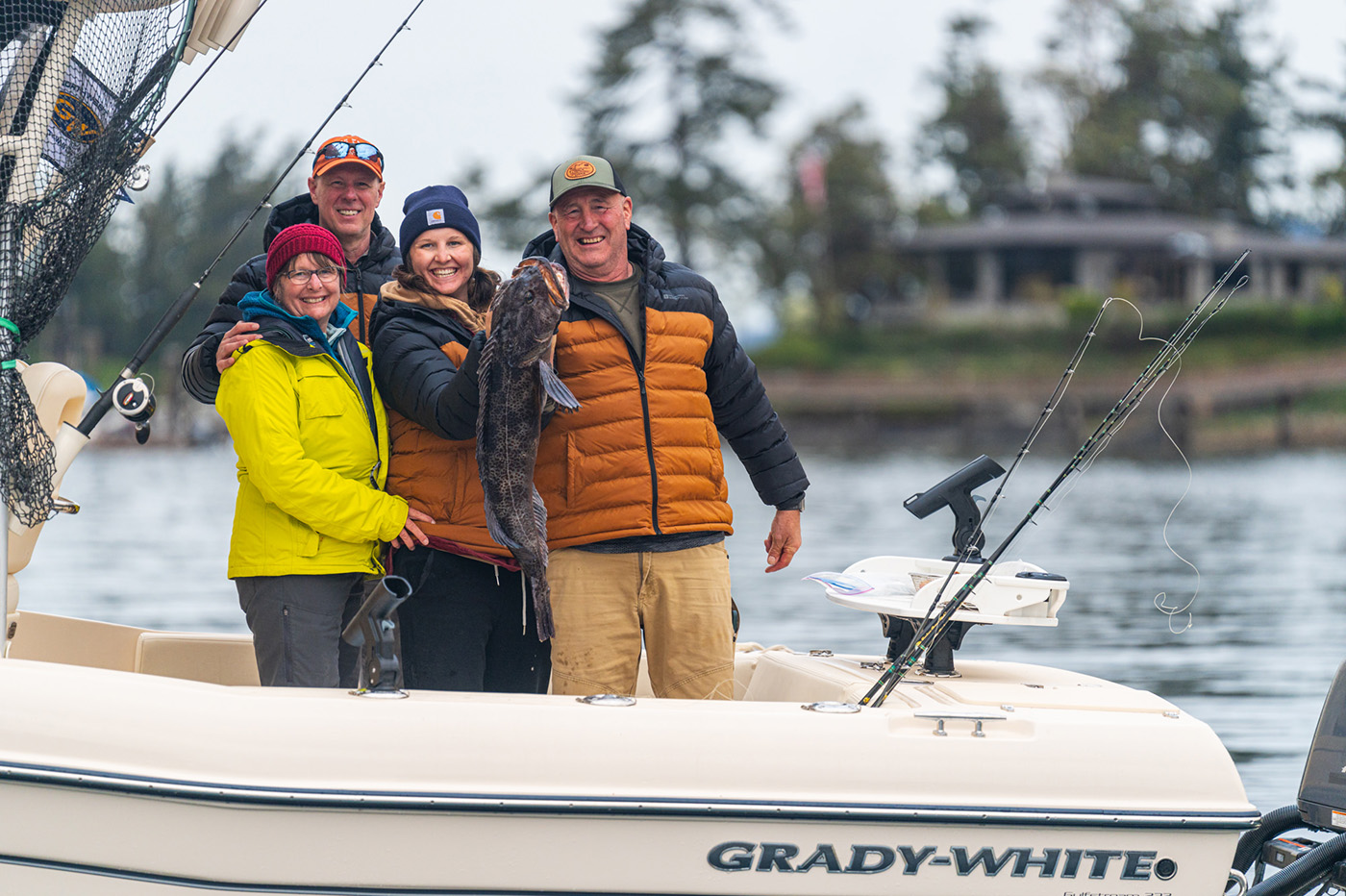 People wearing cold weather gear and holding up a fish in the cockpit of a Grady-White boat