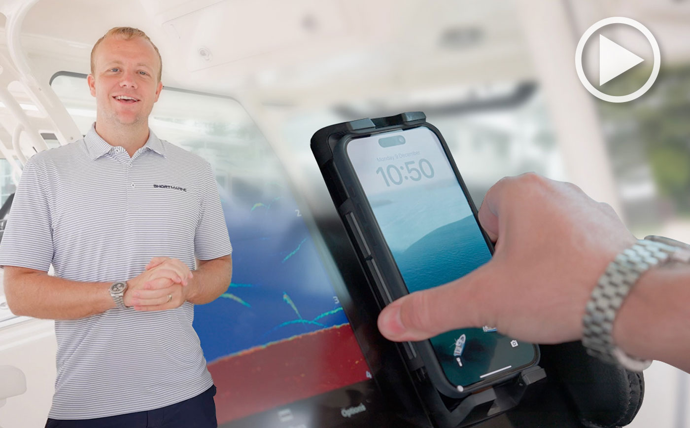 Man at the helm of a Grady-White boat demonstrating phone charging feature