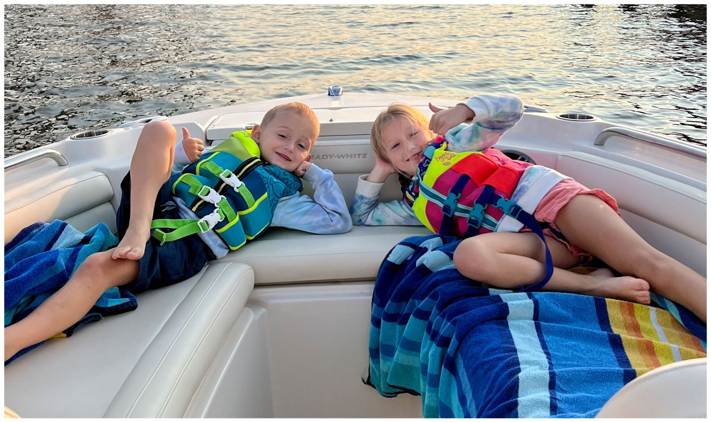Four boys wearing PFDs sitting in the bow of a Grady-White boat