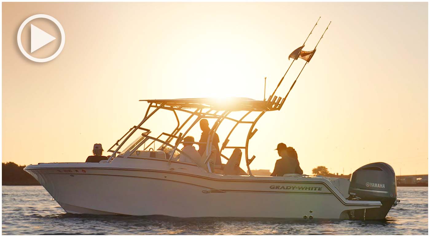 Grady-White dual console on the water port side at sunset with several people aboard