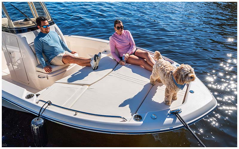 Two people and a dog in the bow of a Grady-White 231 Coastal Explorer